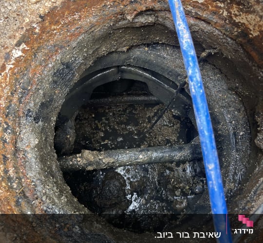 צינור כחול בתוך פתח ביוב חלוד